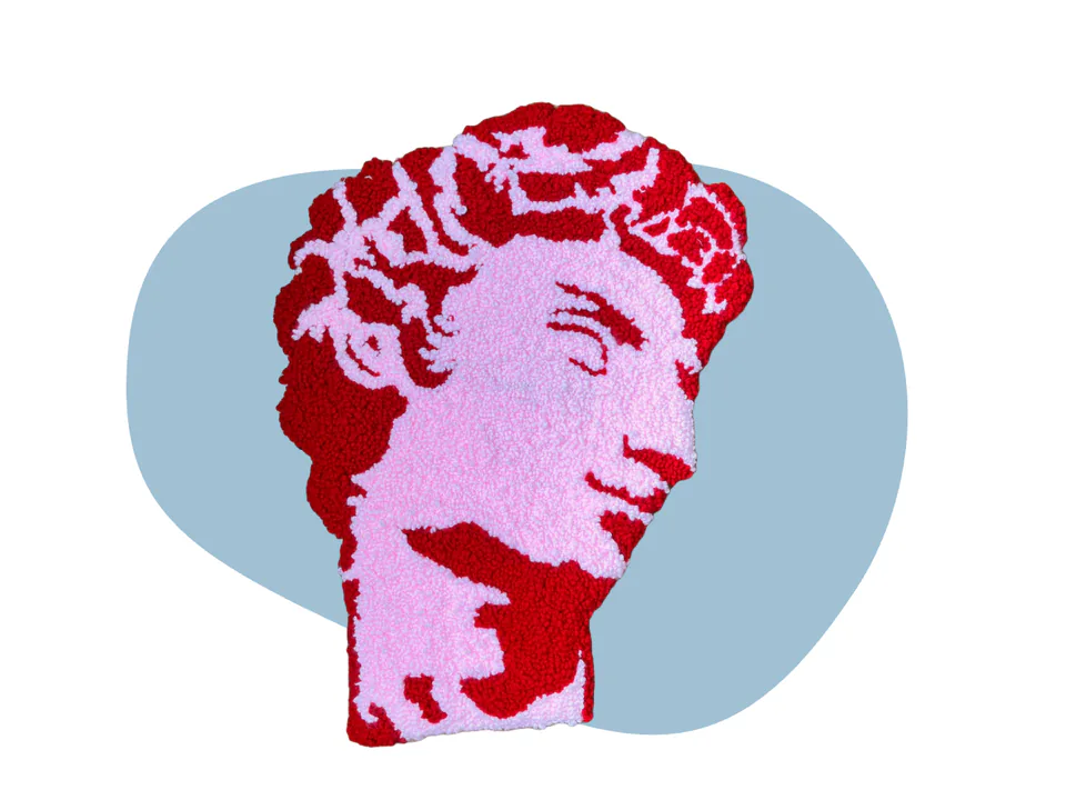 A punch-needle textile portrait of the head of Michelangelo’s David, worked in pink and deep red yarn, on a pale blue backdrop.