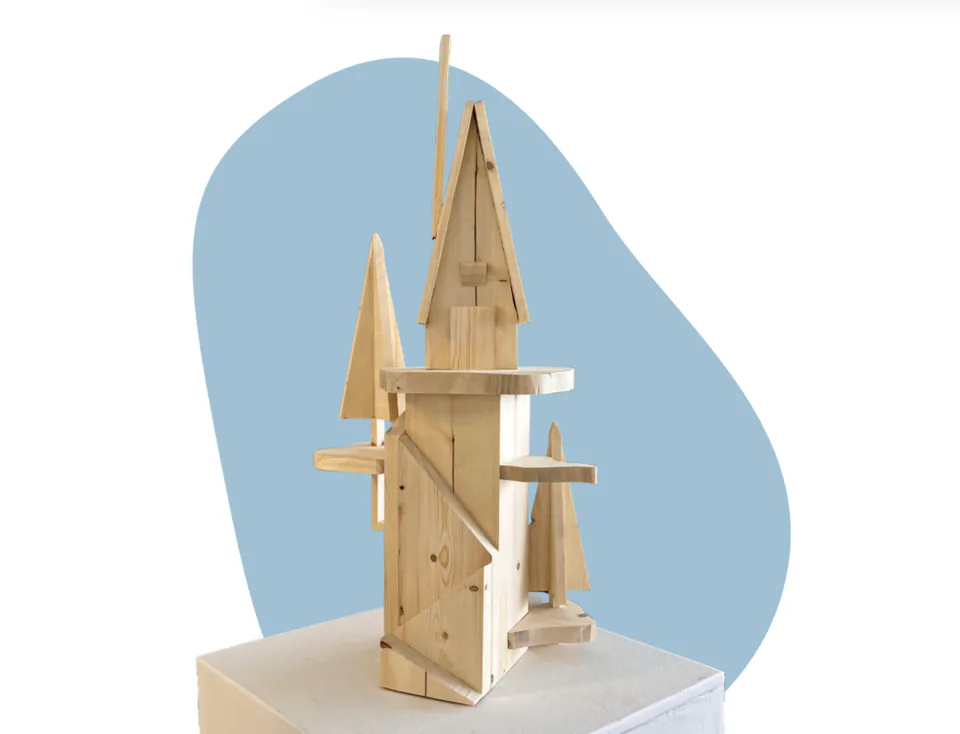 A slender tower built from stacked and joined wooden slats, tapering to a spire, on a pale blue backdrop.