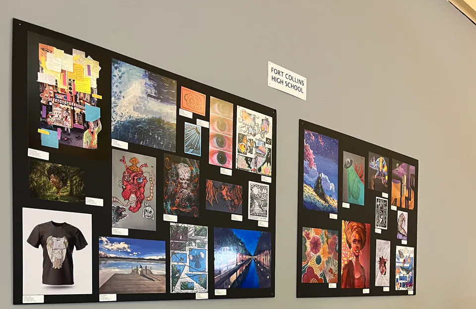 A corridor gallery wall hung with framed student photographs and paintings.
