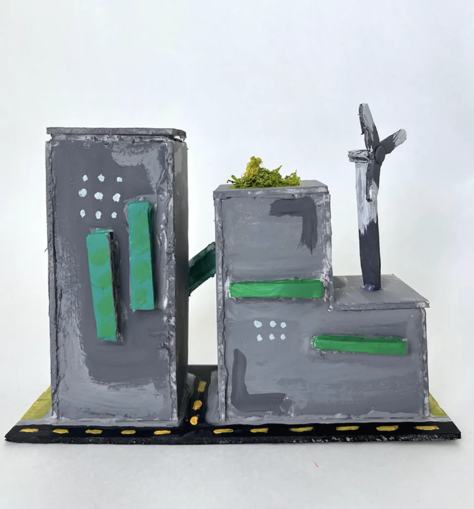 A foam core architectural model of a grey city block with towers, mounted on a road base.