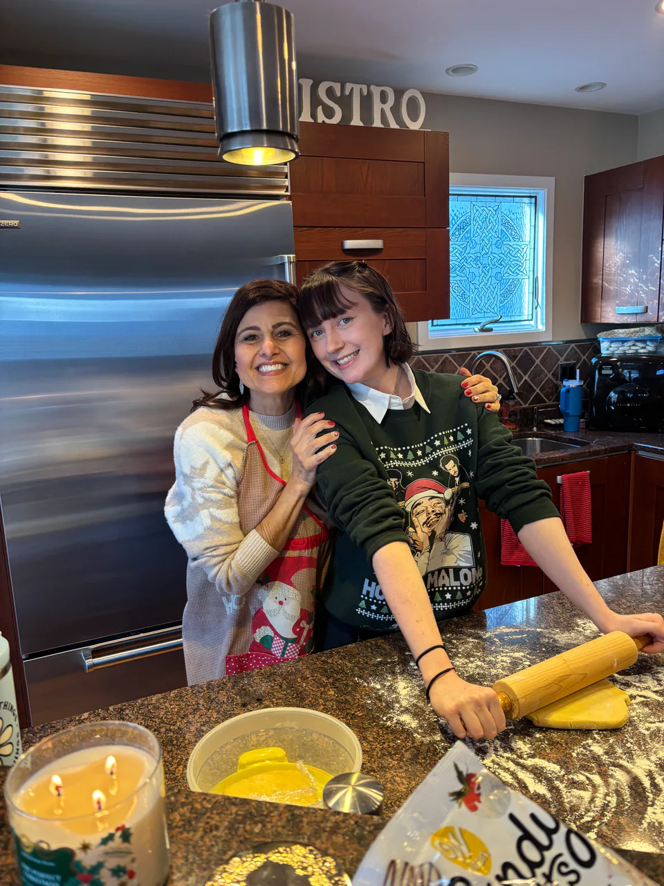 Sarah and a friend baking together at a kitchen island, rolling pin and mixing bowls in front of them.